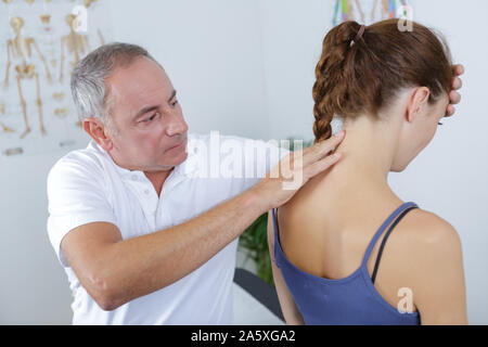 Männliche Physiotherapeuten auf junge weibliche Patienten zurück Stockfoto