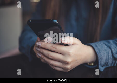 Closeup Bild einer Frau halten, die Verwendung und die Ergebnisse smart phone auf Tisch Stockfoto