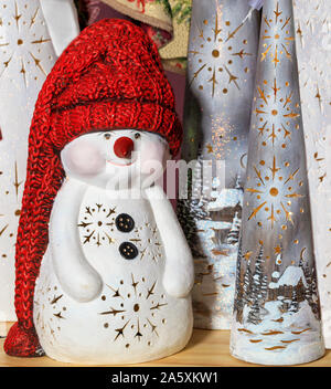 Dekorative Spielzeug Schneemann in einem langen roten Strickmütze, Silvester vor dem Hintergrund von Weihnachten, das neue Jahr kappen. Stockfoto