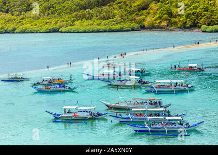 Tropische Insel Landschaft mit vielen bangca traditionelle Philippinen Boote am Ufer voller Touristen verankert, Vigan Insel, Palawan, Philippinen Stockfoto