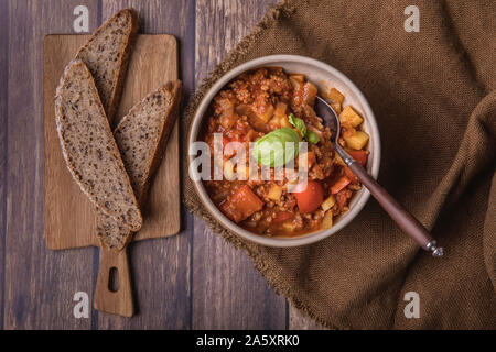 Dicke Suppe oder Brühe mit Hackfleisch, Kartoffeln, Tomaten und Paprika. Neben der Suppe sind einige Scheiben von hausgemachten Sauerteigbrot und Frische Stockfoto