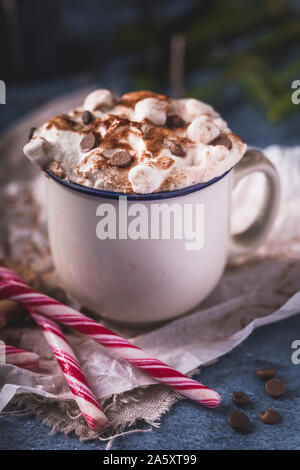 Luxuriöse heiße Schokolade mit Sahne und Stücke von Marshmallows und Chocolate Chips, in eine weiße Tasse auf einem blauen Hintergrund. Vor dem chocol Stockfoto