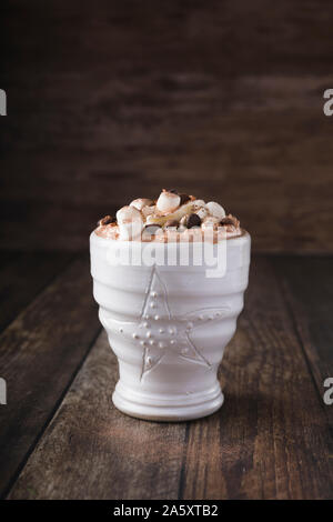 Eine weiße Tasse mit luxuriösen Heiße Schokolade mit Sahne und Stücke von Marshmallows und Chocolate Chips. Horizontale schoß leicht von oben. Minderen Stockfoto