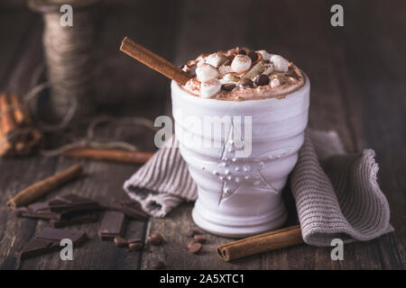 Eine weiße Tasse mit luxuriösen Heiße Schokolade mit Sahne und Stücke von Marshmallows und Chocolate Chips. Stücke Schokolade sind rund um o verstreut Stockfoto
