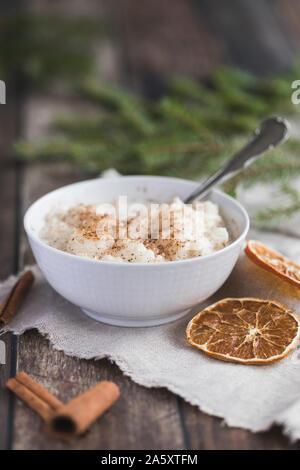 Traditionelle Milchreis auch als tomtegröt oder schwedische risgrynsgröt bekannt. Der Milchreis ist in einem weißen Porzellan Schüssel auf einem dunklen Holztisch mit Stockfoto