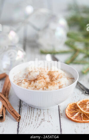 Traditionelle Milchreis auch als tomtegröt oder schwedische risgrynsgröt bekannt. Der Milchreis ist in einem weißen Porzellan Schüssel auf eine weiße Holztisch, mit Stockfoto