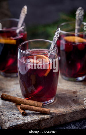 Glühwein Mit Zimtstangen, getrocknete Orangen und Preiselbeeren. Die Gläser sind auf einem Kalk Hintergrund mit einem Green Pine Tree Branch in der Rückseite Stockfoto