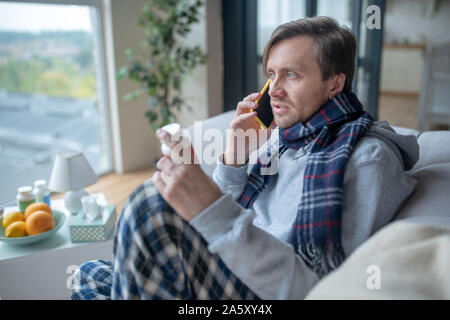 Mann mit Schal Gespräch mit dem Arzt am Telefon Stockfoto