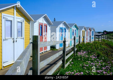 Mehrfarbige Umkleidekabinen am Strand mit Promenade mit Blick auf den Strand an der Bude Cornwall England Stockfoto