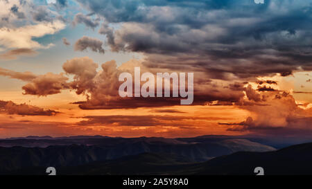 Dramatischen Licht durch die Wolken vor dem Hintergrund einer spannenden, lebendigen stürmischen Himmel bei Sonnenuntergang, bei Dämmerung in den Bergen. Panorama, natürliche Composit Stockfoto