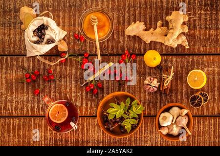 Tasse Kräutertee auf Holz- Hintergrund. Die traditionelle Medizin, Grippe Konzept. Hagebutte Tee gegen Erkältung und Grippe. Therapie der Influenza. Grippeepidemie. Stockfoto