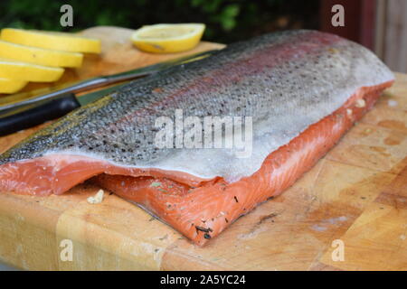 Zwei frische Lachsfilets mit Haut auf Holz Schneidebrett. In Scheiben geschnittene Zitrone auf Hintergrund. Stockfoto