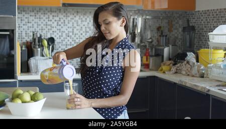 Frau gießen Saft aus der Kanne auf Glas Stockfoto