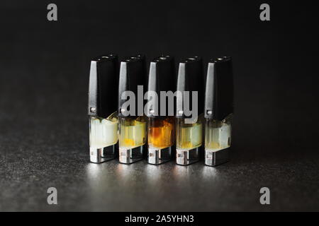 E-Saft vape nachfüllen Pods mit Flüssigkeiten mit verschiedenen Schattierungen von Orange Gelb, Schwarz Hintergrund Nahaufnahme Stockfoto