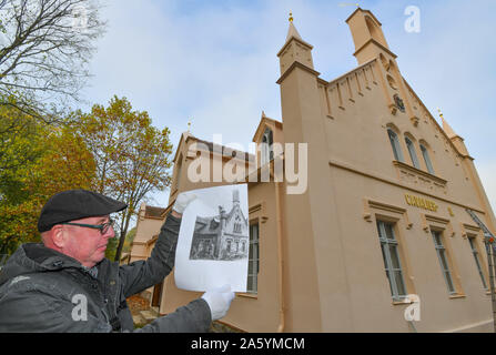 Cottbus, Deutschland. 23 Okt, 2019. Jens-Uwe Möbert, Restaurator der Fürst-Pückler-Museum Park und Schloss Branitz Stiftung, zeigt ein Foto von 1985 der alten Gebäude im Branitzer Park anlässlich der Pressekonferenz "Baufortschritt auf dem Cavalierhaus". Seit Anfang 2019, dem cavalierhaus an Schloss Branitz wurde umfassend renoviert. Neben dem Dach, Fassade und Gebäude Dekoration, den gesamten Innenraum des neo-gotischen Gebäude wird voraussichtlich im Frühjahr 2020 renoviert werden. Foto: Patrick Pleul/dpa-Zentralbild/ZB/dpa/Alamy leben Nachrichten Stockfoto