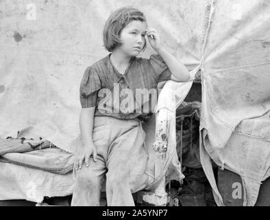 Kind der Wanderarbeitnehmer sitzen auf dem Bett im Zelt home aus Baumwolle pflücken Säcke, Harlingen, Texas von Russell Lee, 1903-1986, Fotograf 19390101 Stockfoto