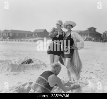 Unbekannter Mann bauen Sandburg und zwei Frauen, Long Beach, New York 1910 von Arnold Genthe 1869-1942, Fotograf Stockfoto