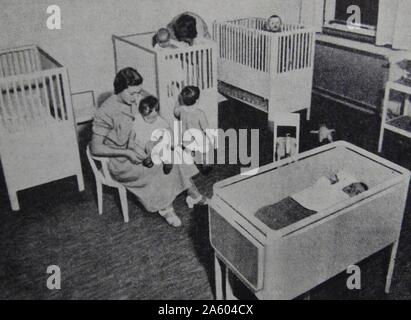 Foto von Krankenschwestern, die Fürsorge für Kinder und Säuglinge in einer Kindertagesstätte. Vom 20. Jahrhundert Stockfoto