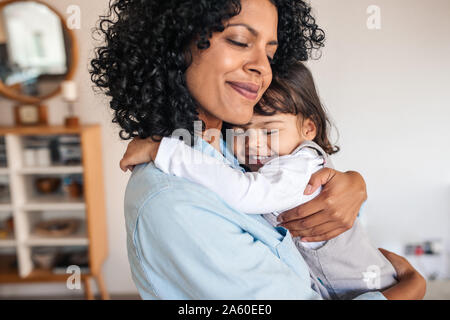 Mutter und ihre kleine Tochter zu Hause umarmen Stockfoto