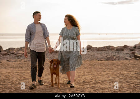 Junges Paar mit Hund am Strand Stockfoto