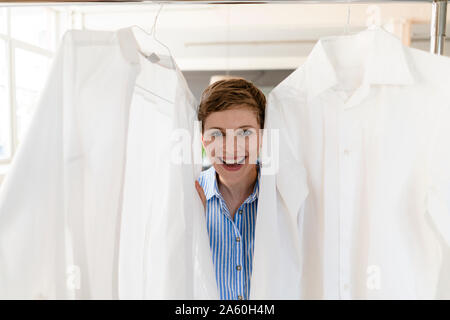 Portrait von Happy Geschäftsfrau, das zwischen zwei weiße Hemden Stockfoto