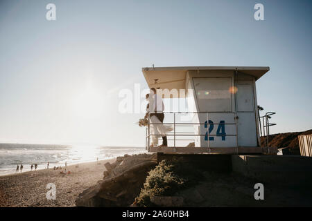 Braut und Bräutigam an lifeguard Hütte am Strand bei Sonnenuntergang Stockfoto