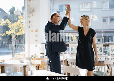 Erfolgreicher Geschäftsmann und Frau, high-fiving in einem Coffee Shop Stockfoto