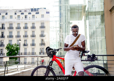 Junger Mann auf seinem Fahrrad mit seinem Smartphone Stockfoto