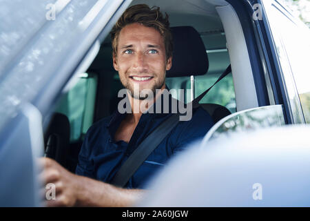 Lächelnder junge Mann im Auto Stockfoto