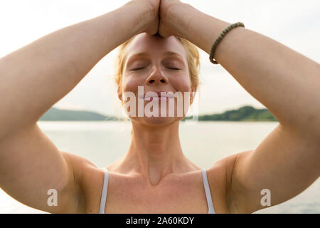 Porträt der jungen Frau mit geschlossenen Augen an einem See Stockfoto