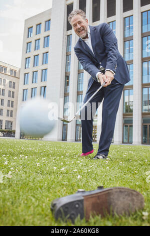 Gerne reife Geschäftsmann Golf spielen auf Rasen in der Stadt Stockfoto