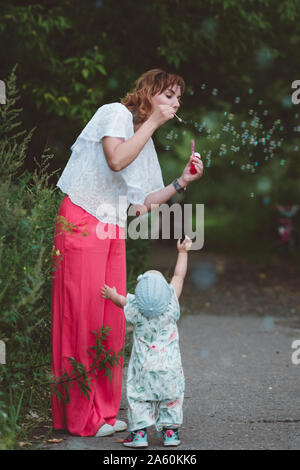 Mutter macht Seifenblasen für ihre kleine Tochter Stockfoto