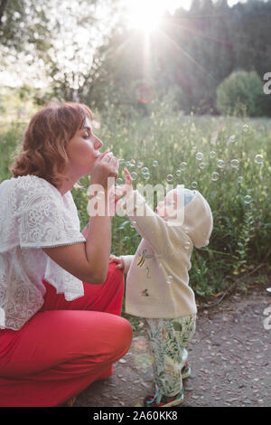 Mutter macht Seifenblasen für ihre kleine Tochter Stockfoto