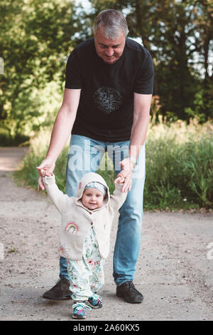 Kleine Mädchen, die ihre ersten Schritte mit ihrem Großvater Stockfoto