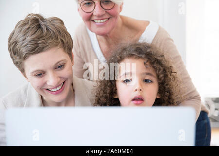 Lächelnde Großmutter, Mutter und Sohn mit Laptop zu Hause Stockfoto