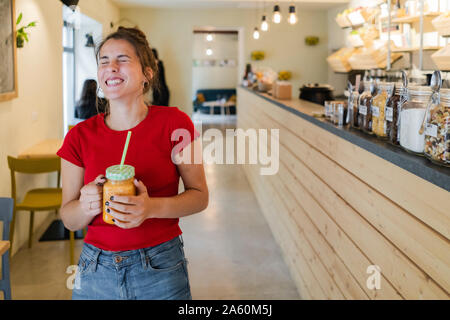 Glückliche junge Frau mit einem Smoothie in einem Cafe Stockfoto