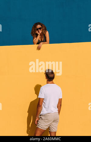 Junge Mann an Frau hinter einem gelben wand suchen Stockfoto