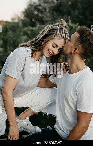 Portrait der junge lächelnde Paar, Mann sie küssen Auf der Stirn Stockfoto