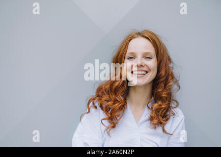 Portrait von Happy rothaarige Frau an einer Wand Stockfoto