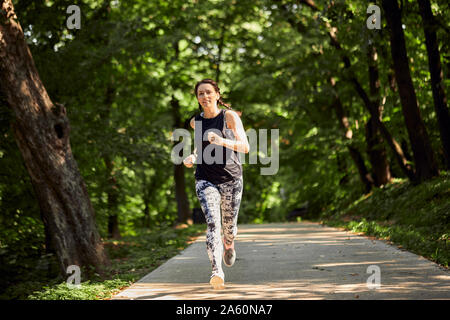 Sportliche junge Frau, die auf Wald Weg Stockfoto