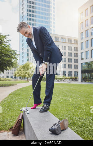 Reifen Geschäftsmann Golf spielen in der Stadt Stockfoto