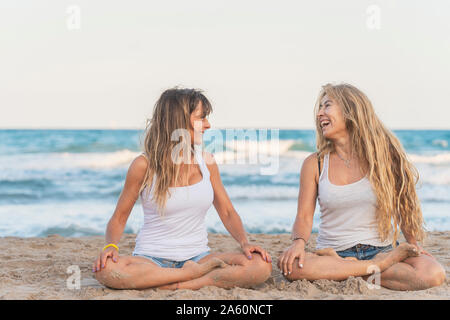 Zwei Frauen praticing Acro Yoga am Strand Stockfoto