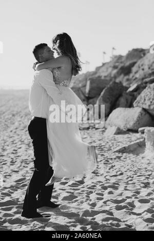 Glückliche Braut und Bräutigam umarmen am Strand Stockfoto