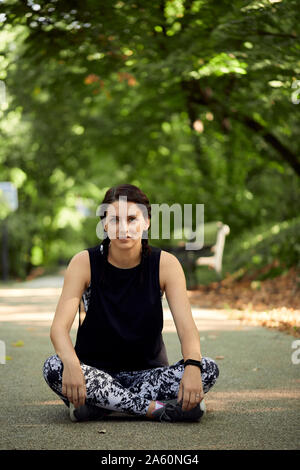 Porträt der sportliche junge Frau sitzt auf den Waldweg Stockfoto
