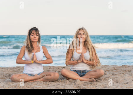 Zwei Frauen praticing Acro Yoga am Strand, meditieren Stockfoto