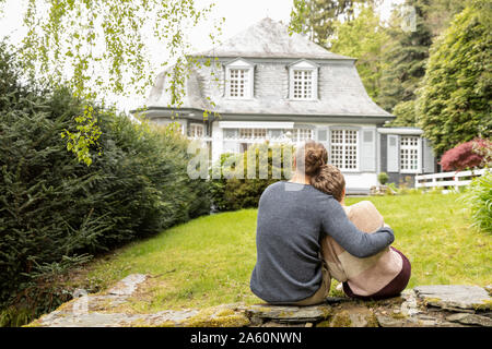 Ansicht der Rückseite des Paar sitzen auf einer Mauer im Garten Stockfoto