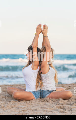 Zwei Frauen praticing Acro Yoga am Strand Stockfoto