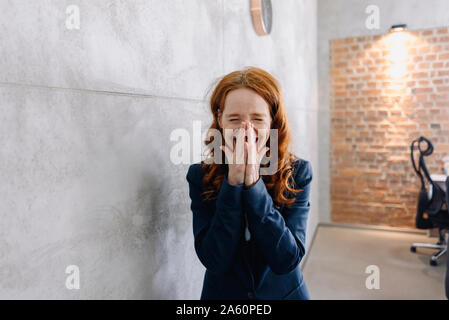 Lachende rothaarige Geschäftsfrau im Büro Stockfoto