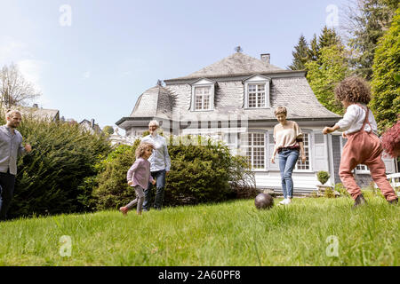 Glückliche Familie Fußball spielen im Garten Stockfoto