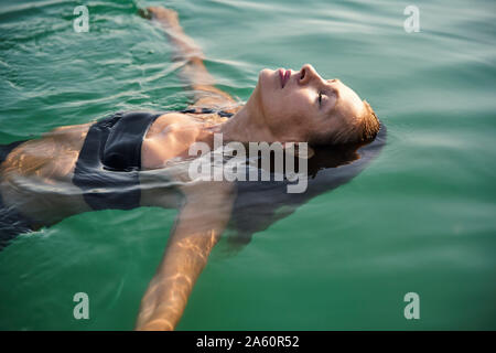 Reife Frau schwimmen in einem See mit geschlossenen Augen Stockfoto